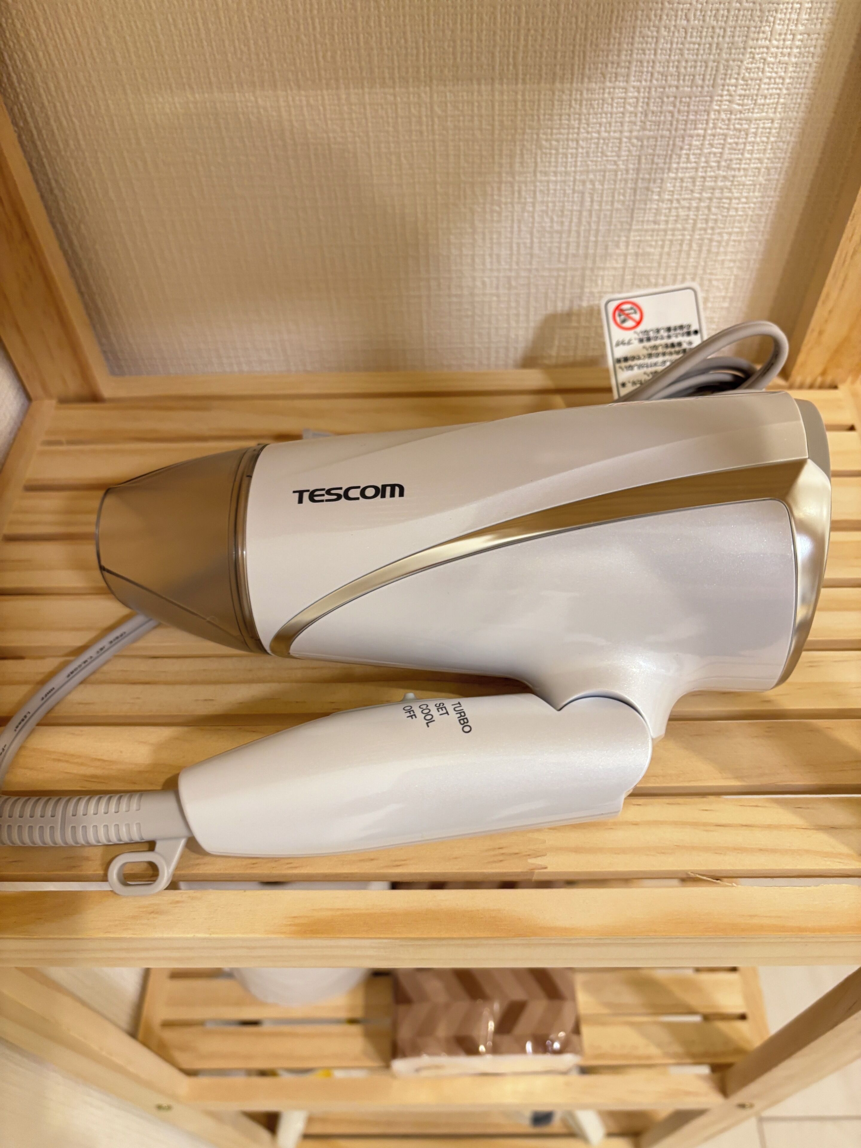 A hair dryer on a wooden shelf with a sign indicating no smoking.