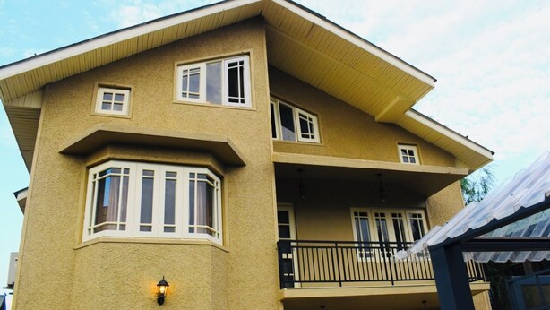 A two-story building with a balcony, a corner window, and a light fixture. - Kohzar (Budgam)