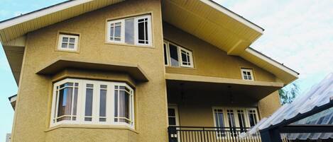 A two-story building with a balcony, a corner window, and a light fixture.