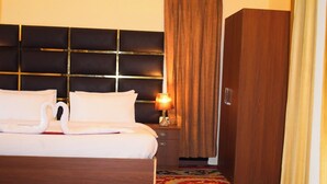 A hotel room with a bed, a nightstand, a lamp, a wardrobe, and a patterned carpet. - Kohzar (Budgam)