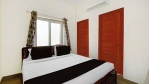 Ein Schlafzimmer mit Bett, einem Fenster mit Vorhängen, einem Kleiderschrank und einer Klimaanlage.