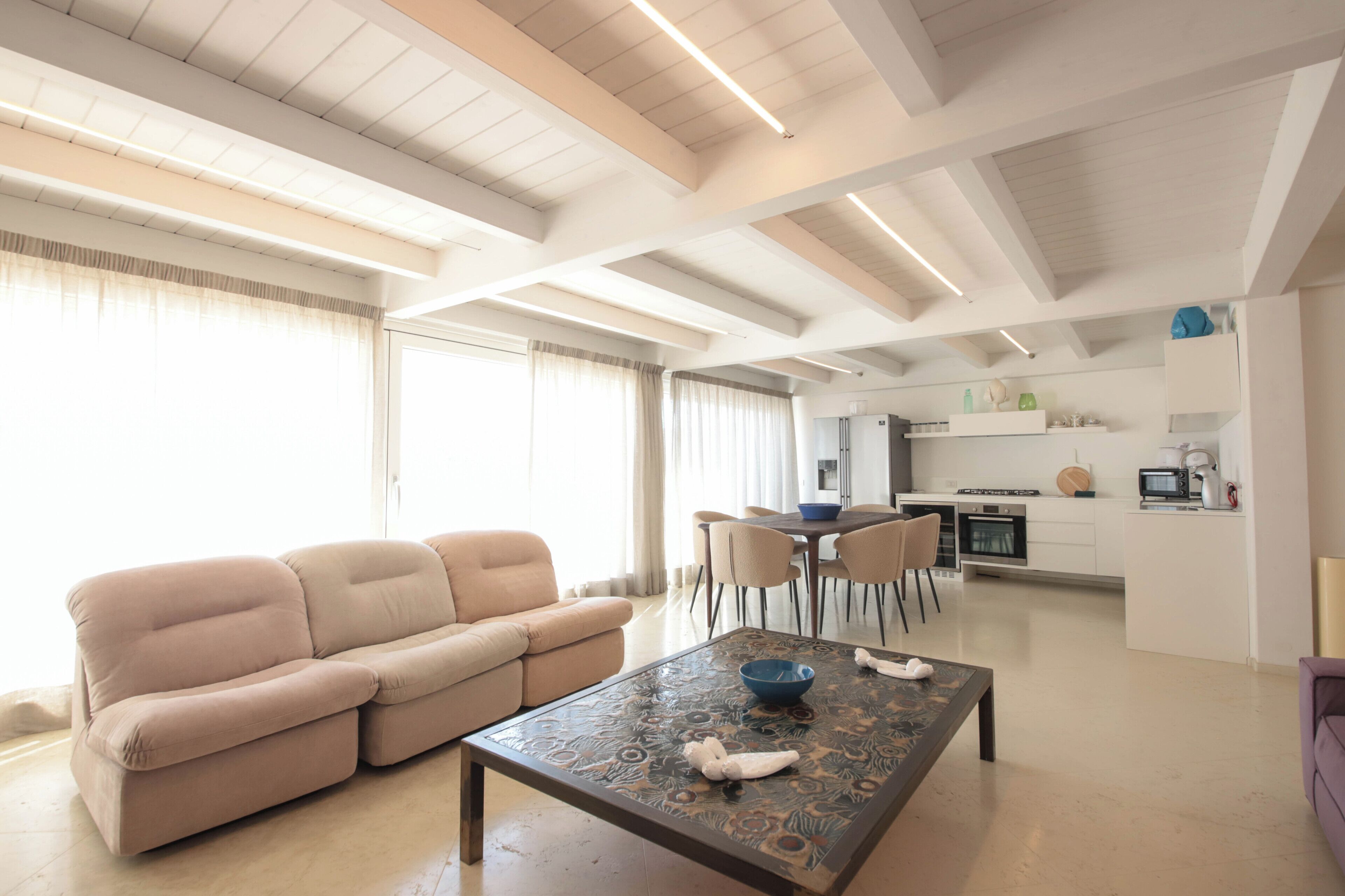 Uma sala de estar moderna com um sofá, uma mesa de centro e um espaço de jantar com cadeiras.