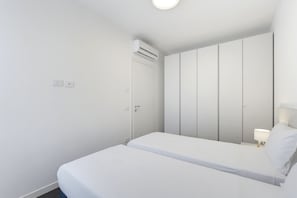Ein schlicht eingerichtetes Hotelzimmer mit Bett, Kleiderschrank und Wand-Klimaanlage.
