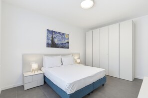 Una camera da letto con un letto, comodini, un armadio e un quadro appeso al muro.