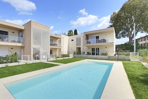 Un edificio residencial con piscina, balcones y un césped bien cuidado.