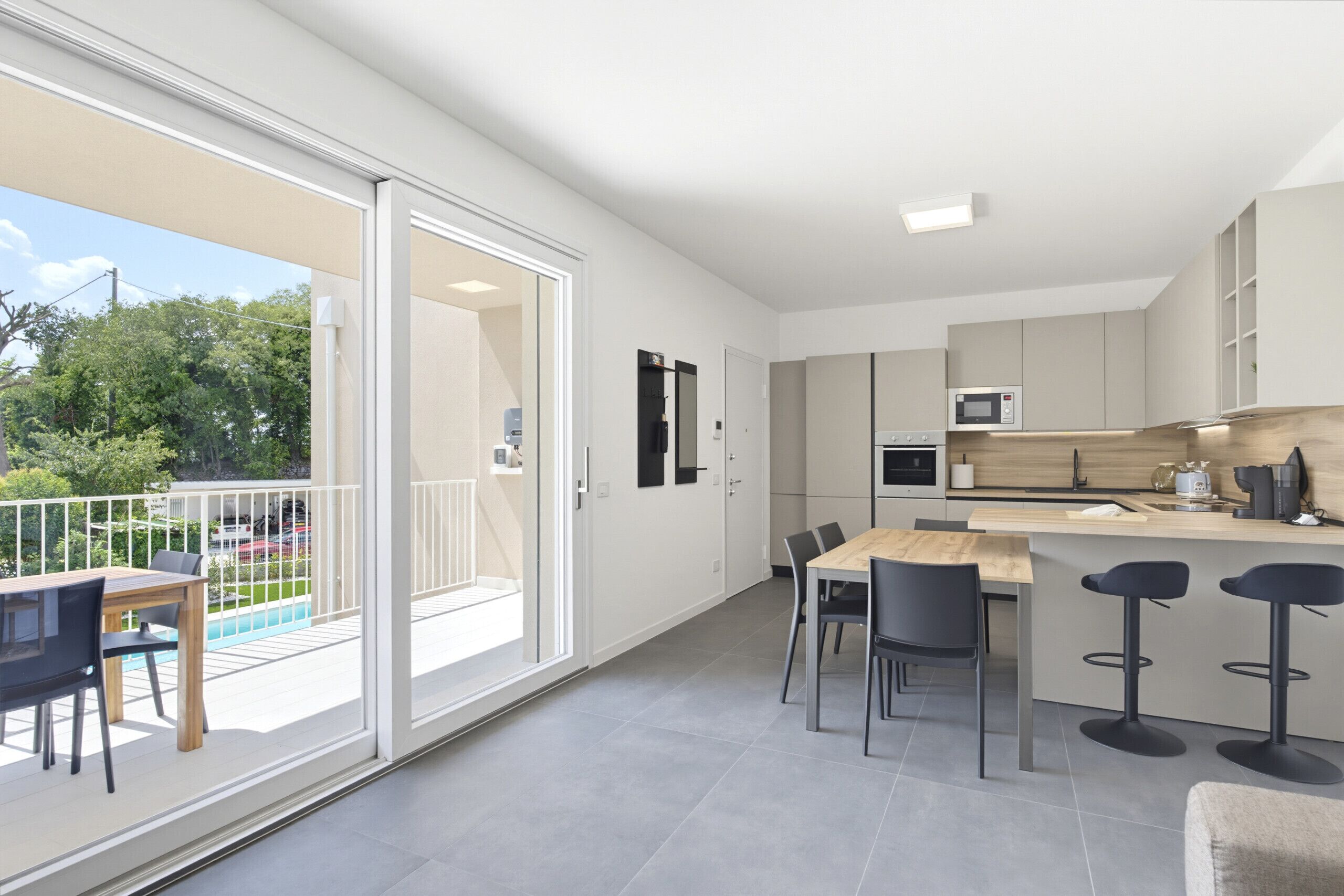 Une cuisine moderne avec un coin repas, un bar et une porte-fenêtre coulissante donnant sur un balcon.