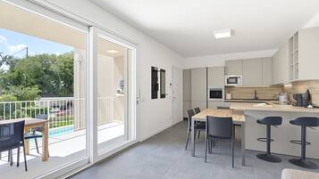 Una cucina moderna con zona pranzo, un bancone e una porta scorrevole in vetro che dà su un balcone.