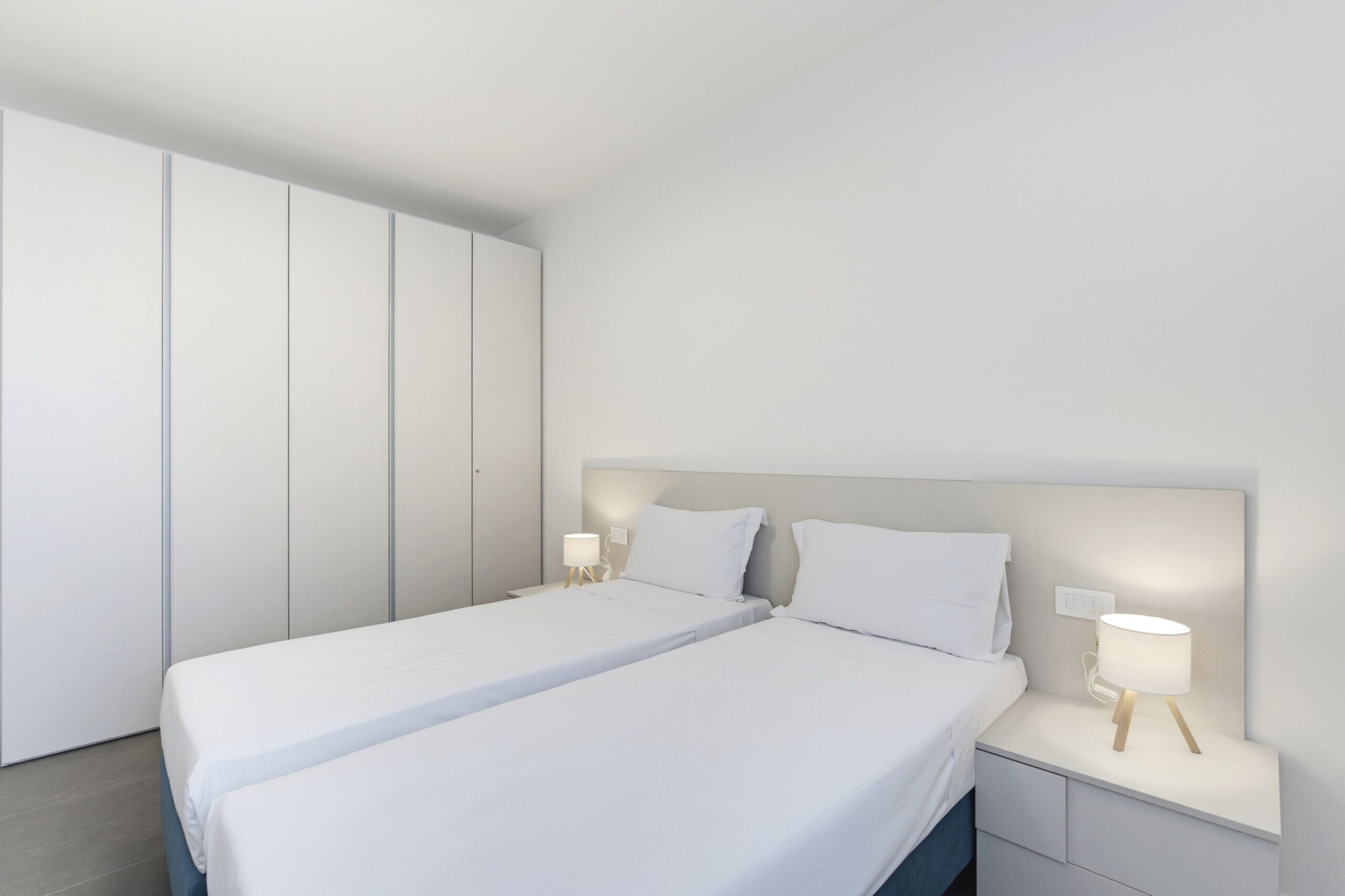Ein modernes Schlafzimmer mit einem großen Bett, zwei Nachttischen und einem Kleiderschrank.
