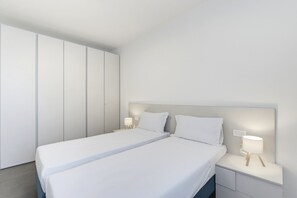 Un dormitorio moderno con una cama grande, dos mesitas de noche y un armario.