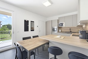 Una cocina moderna con una isla central, taburetes de bar y una mesa de comedor con sillas.