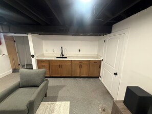 Ein kompakter Wohnraum mit Küchenzeile, einer Couch und einer Tür.