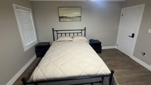 Ein Schlafzimmer mit einem Bett, einem Nachttisch, einem Deckenventilator, einer Wanduhr und einer Tür.