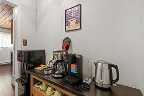 A kitchenette with a coffee machine, kettle, and a framed picture on the wall.