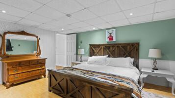 A bedroom with a wooden bed, a dresser, a mirror, and a wall with a picture.