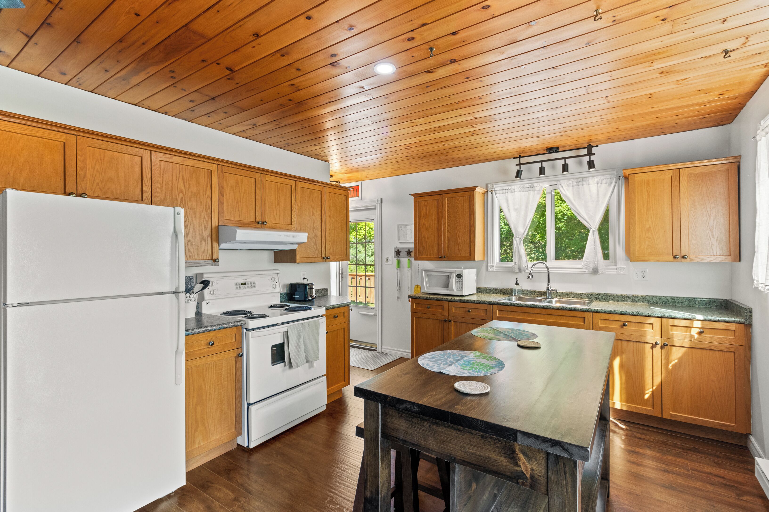 A kitchen with wooden cabinets, a white refrigerator, a stove, and a microwave.