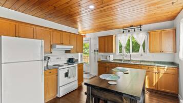 A kitchen with wooden cabinets, a white refrigerator, a stove, and a microwave.