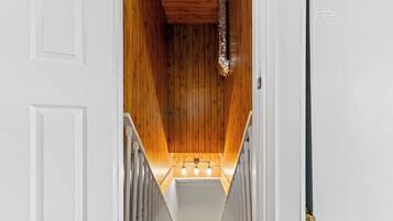 A wooden staircase with a white door at the top and a light fixture at the bottom.