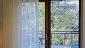 A hotel room with a bed, a sliding glass door leading to an outdoor seating area with tables and chairs.