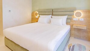 Une chambre d’hôtel avec un grand lit, une tête de lit en bois dotée d’un éclairage intégré et une petite table de chevet.