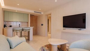 Un salon moderne avec un canapé, une table basse et un téléviseur fixé au mur.