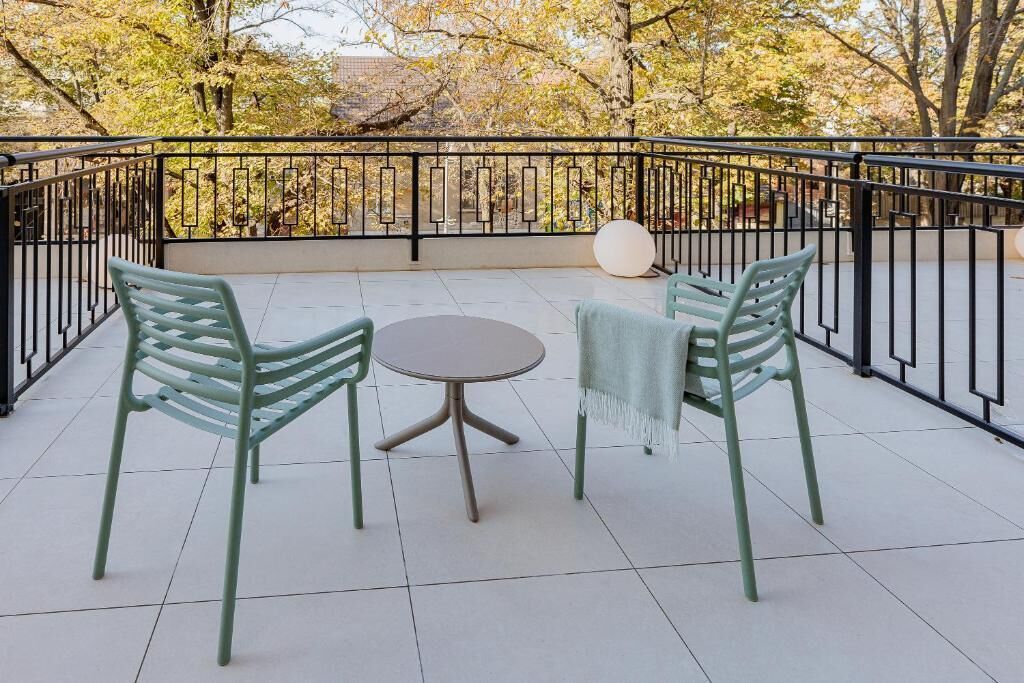 A balcony with two chairs and a table, surrounded by a black metal railing.