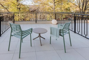 A balcony with two chairs and a table, surrounded by a black metal railing.