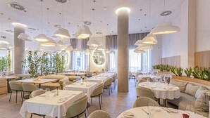Un restaurant avec des tables rondes, de hauts plafonds et des luminaires suspendus.