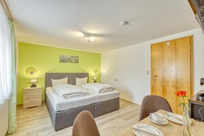 A hotel room with a bed, bedside lamps, a desk with a chair, and a wooden door.