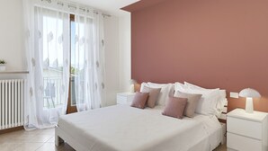 Une chambre à coucher avec un lit, des tables de chevet, une lampe, une plante en pot et une vue sur l’extérieur.