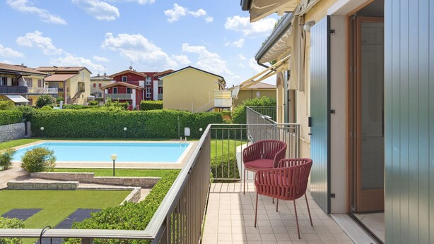 Il s’agit d’une propriété résidentielle dotée d’une piscine, d’un patio couvert avec des chaises et offrant une vue sur les maisons voisines.