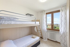Ein Schlafraum mit Etagenbett, Fenster und Blick ins Freie.