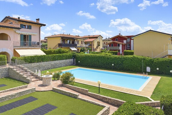 A residential area with a swimming pool, stone steps, and a stone wall. - Regarda - Basiliko Cosy Apartment with pool, pets allowed (Lazise)