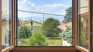 Une fenêtre donnant sur un quartier résidentiel, avec vue sur des maisons et des arbres.