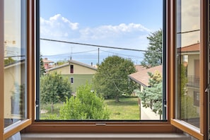A window with a view of a residential area, including houses and trees. - Regarda - Basiliko Cosy Apartment with pool, pets allowed (Lazise)