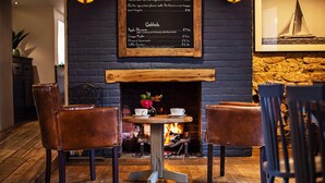 Un comedor acogedor con pared de ladrillo, chimenea y una pizarra con el menú.