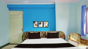 Ein Hotelzimmer mit einem großen Bett, zwei schwarzen Kissen, einer blauen Akzentwand und drei gerahmten Bildern.