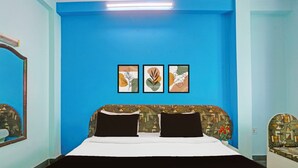 Ein Schlafzimmer mit blauer Wand, einem Bett mit schwarz-weißer Bettwäsche und drei gerahmten Kunstwerken über dem Bett.