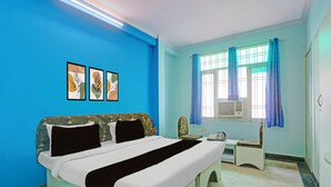 Ein Schlafzimmer mit einem Bett, einem Nachttisch, einem Sessel und einem Fenster mit Vorhängen.