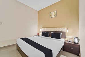 A hotel room with a bed, bedside table, lamp, and a kettle. - Collection O Kalady Near Airport (Aluva)