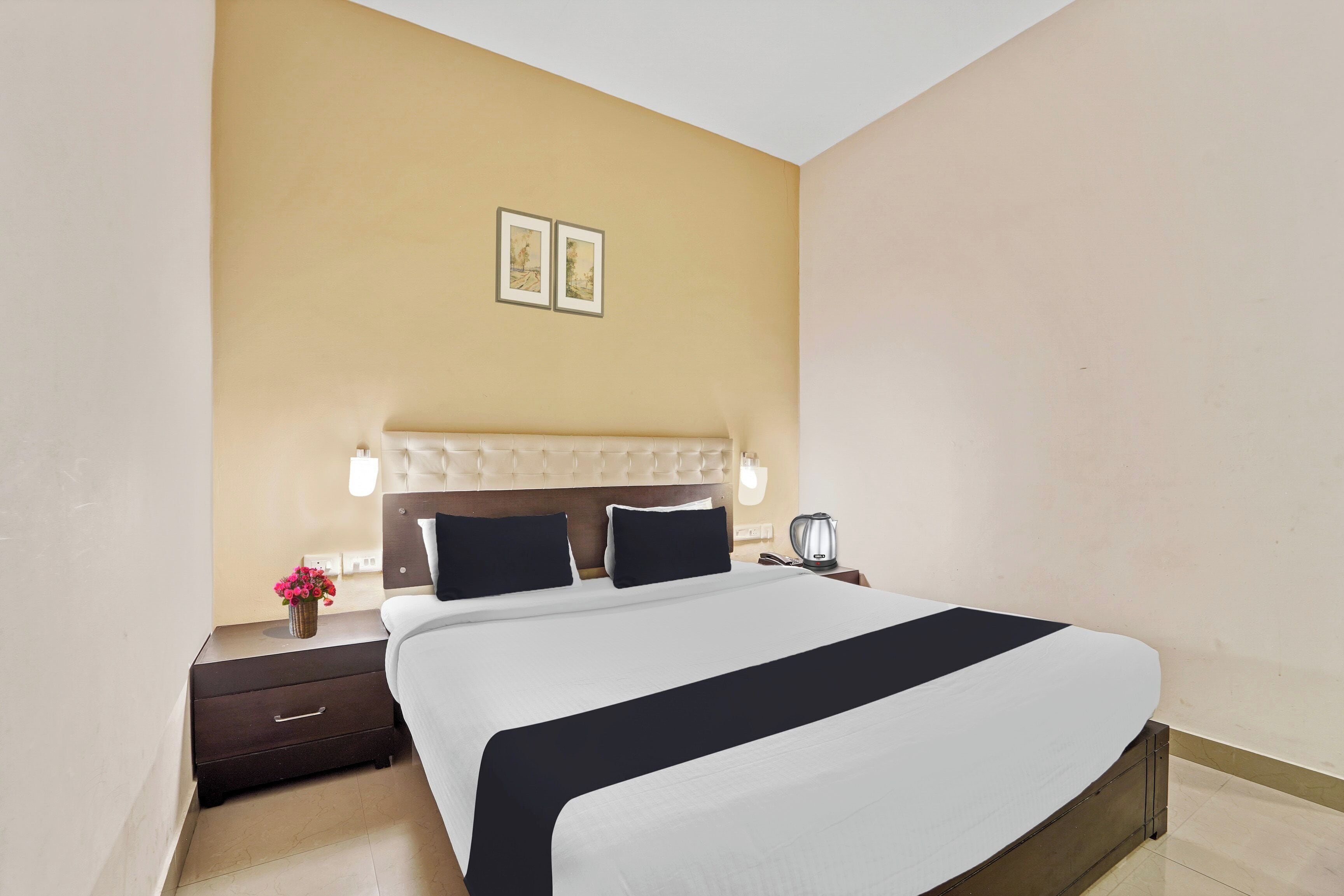 Habitación de hotel con una cama grande, una mesita de noche, una lámpara y un cuadro en la pared.