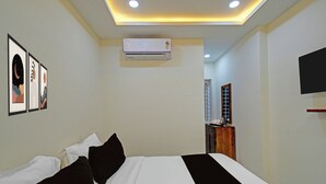 A hotel room with a bed, a flat-screen TV mounted on the wall, and an air conditioning unit. - Super Collection O Hyderabad Central (Hyderabad)