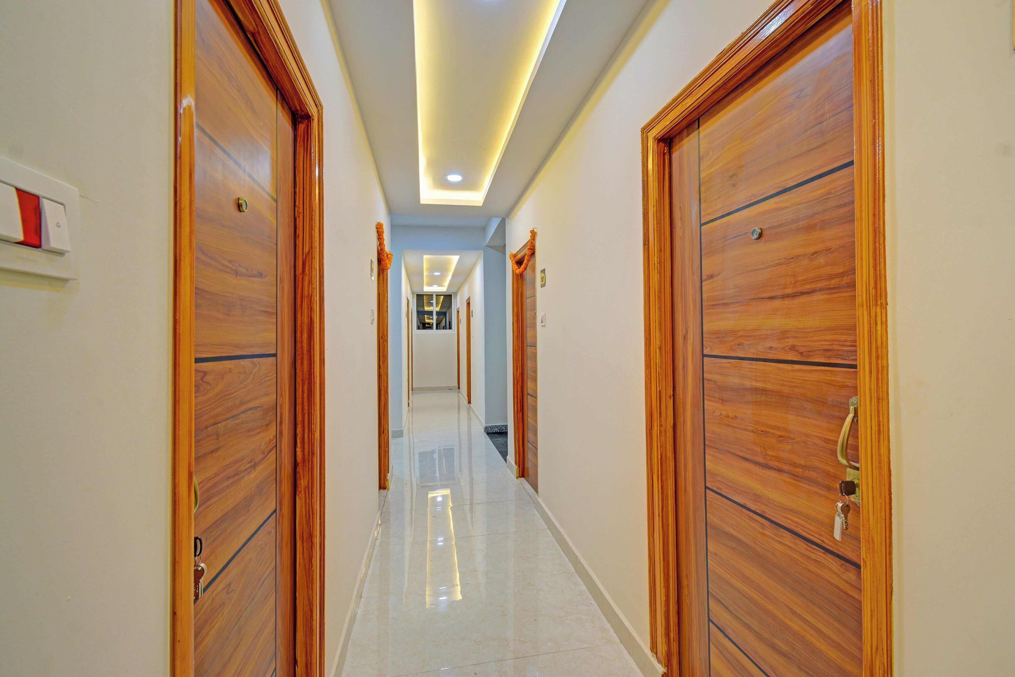 A hallway with wooden doors and a tiled floor, leading to a room with a bed.