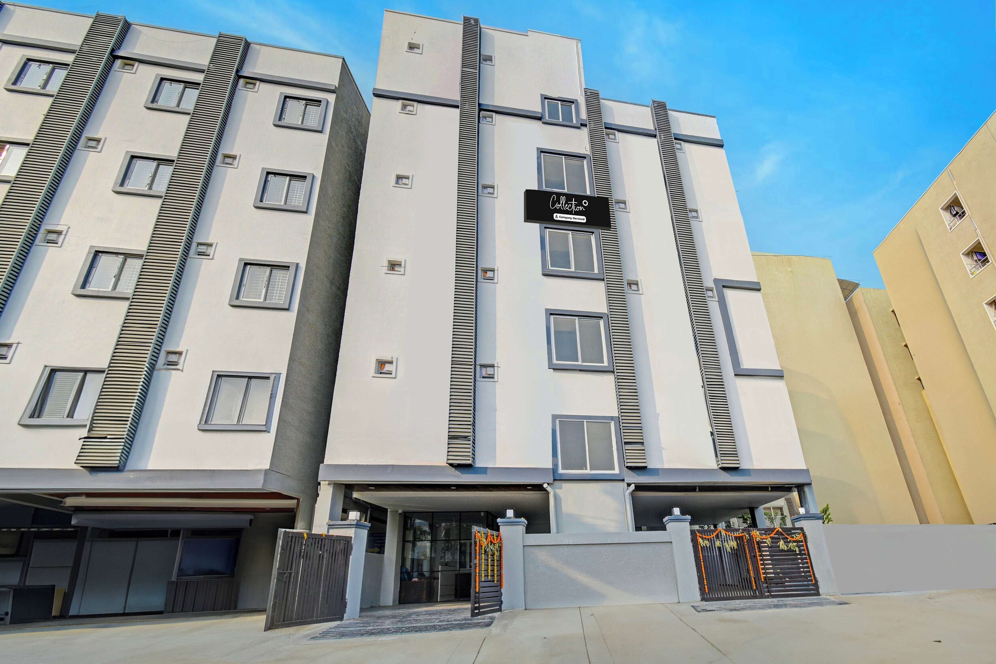 A multi-story residential building with a modern facade, a gated entrance, and a sign indicating a company service.