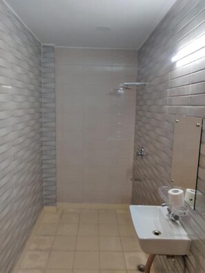 A bathroom with a shower, a toilet, and a sink with a mirror. - Heistel Delhi (New Delhi)