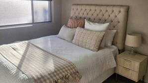 A bedroom with a bed, a nightstand, a lamp, and a ceiling fan. - Tidy one bedroom apartment (Leeton)