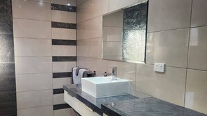 A modern bathroom with a white sink, dark marble countertop, and a mirror above it. - Tidy one bedroom apartment (Leeton)