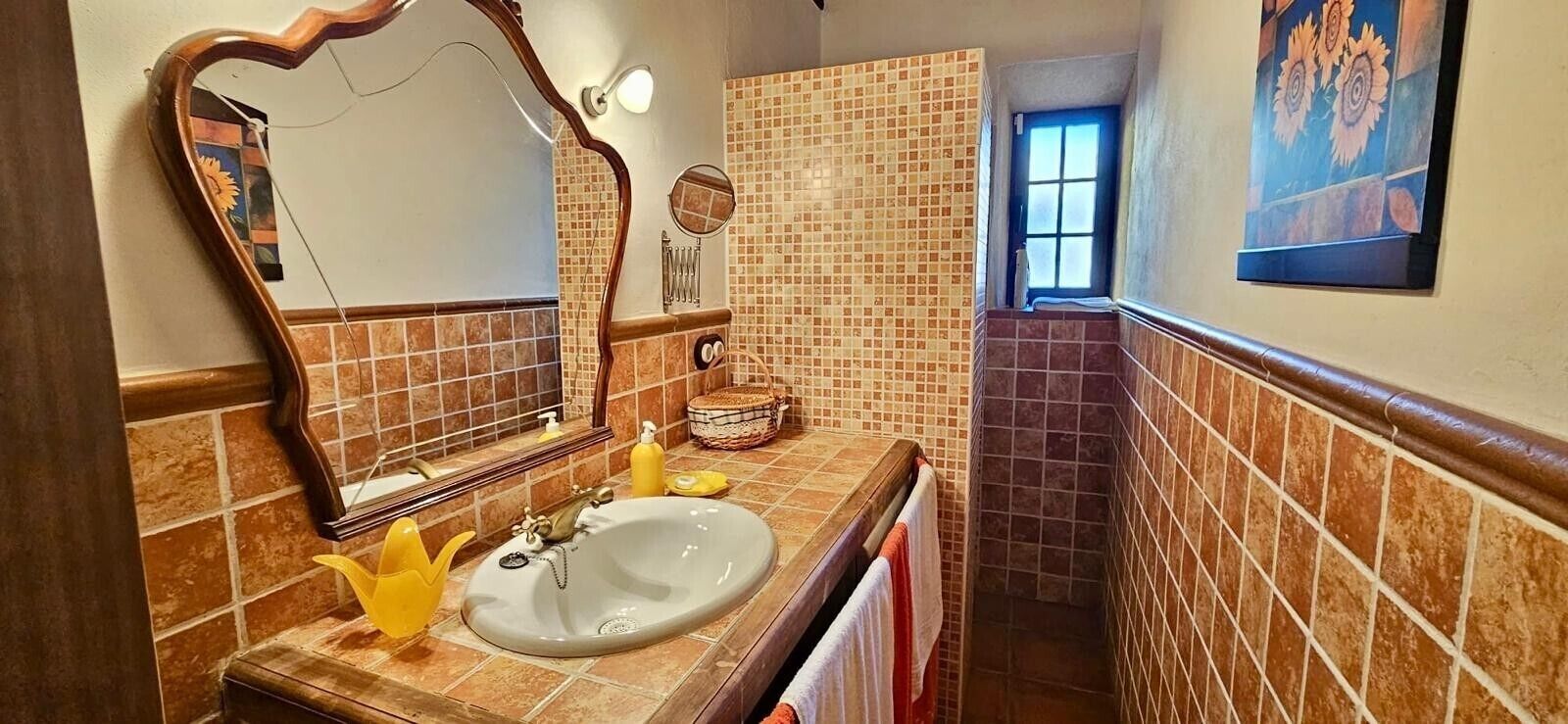 A bathroom with a large mirror, a sink, and a window.