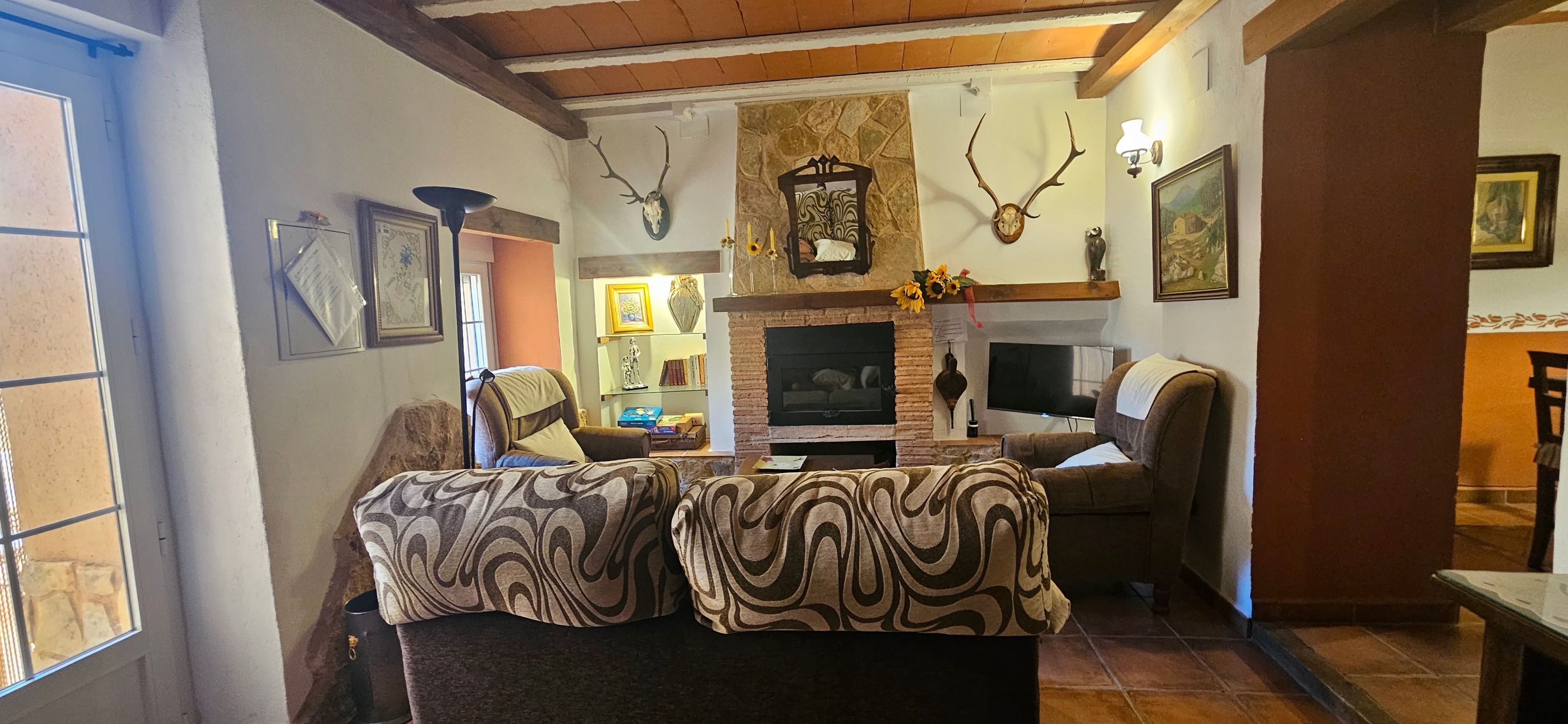 Un salon chaleureux avec une cheminée, deux canapés et des bois de cerf accrochés au mur.