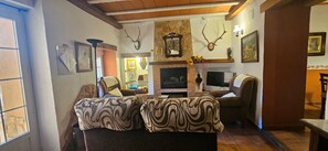 Una sala de estar acogedora con chimenea, dos sofás y cuernos de ciervo en la pared.