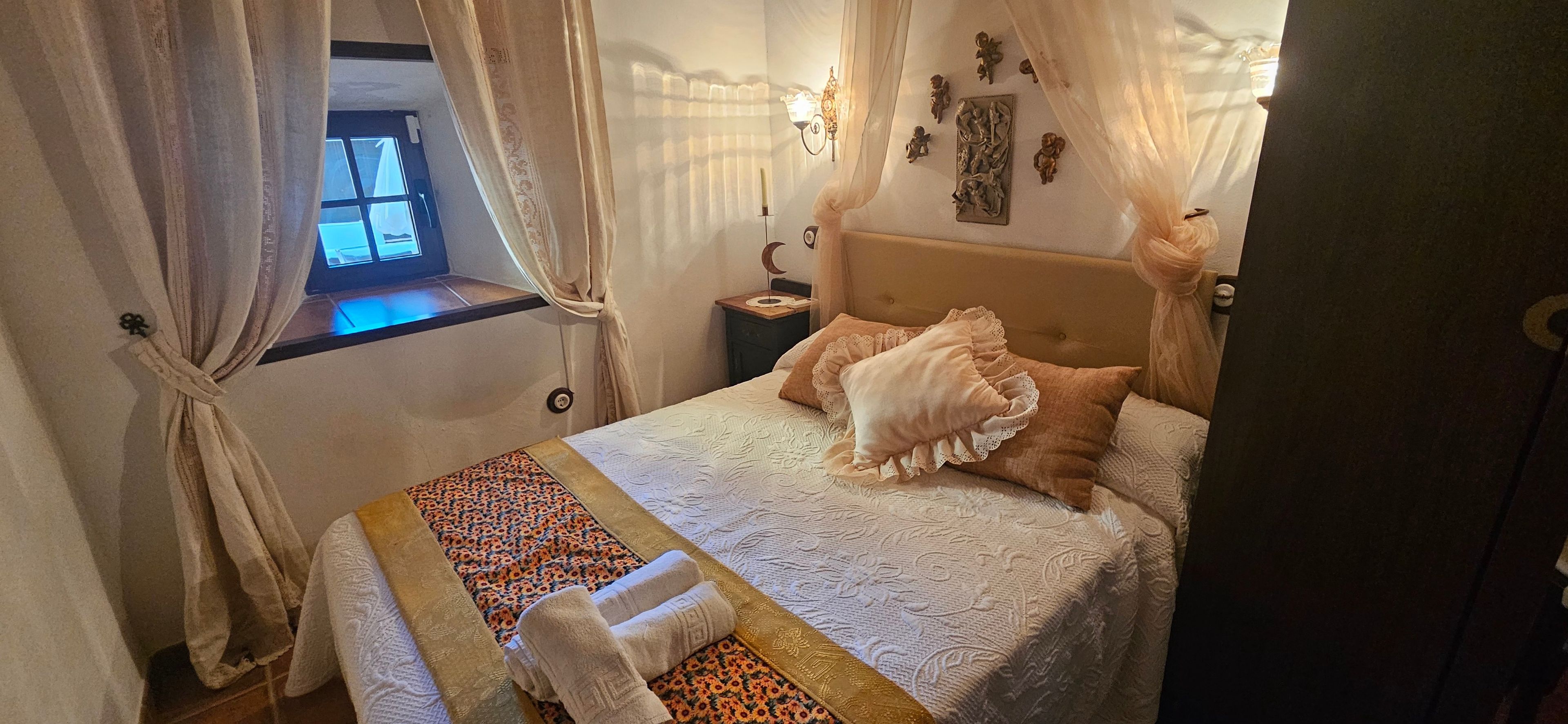 A bedroom with a bed, curtains, a window, and wall decorations.